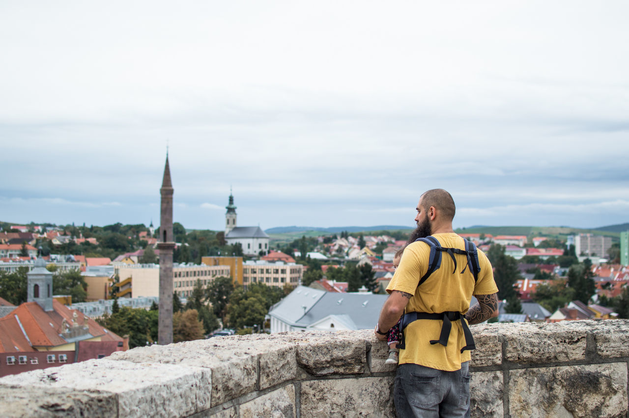 REAR VIEW OF MAN LOOKING AT CITYSCAPE