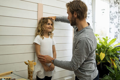 Father measuring daughter's height at home