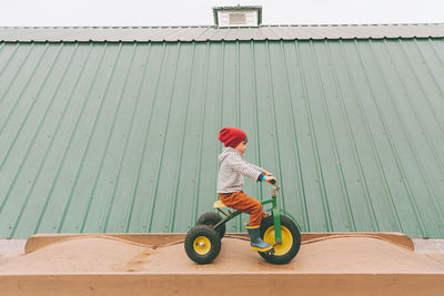 Side view of boy riding tricycle outdoors