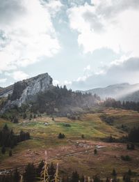 Scenic view of field and house on mountains against sky and sun light