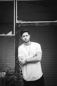 Portrait of young man standing against wall