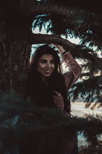 Portrait of a smiling young woman against trees