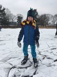 Full length portrait of boy playing on snow covered field