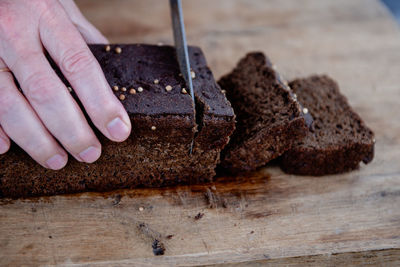 Sliced rye bread stock photo. the man cuts whole-wheat rye bread on a wooden cutting board.