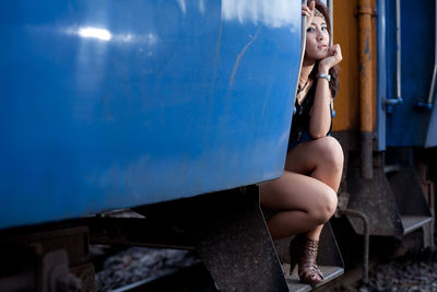 Fashionable woman sitting on train door