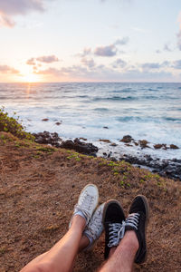View of couple shoes by the ocean during sunrise