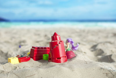 Red toy on sand at beach against sky