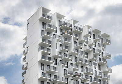 Low angle view of modern buildings against cloudy sky