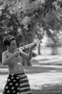 Full length of shirtless boy holding umbrella