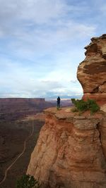 Man standing on cliff against sky