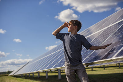 Boy standing next to solar panels