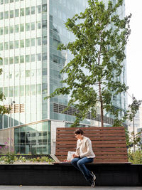 Business woman in urban park with laptop and cardboard cup of coffee. student learns remotely.