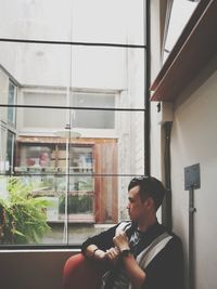 Young man sitting by window