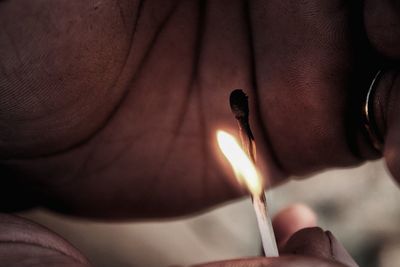 Close-up of hand holding burning candle