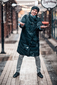 Full length portrait of young man standing in snow