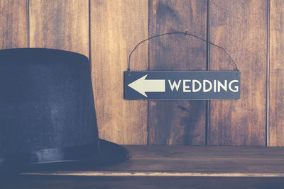Close-up of hat against wedding sign on wooden shelf