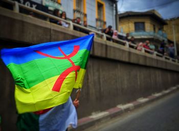 Cropped image of man holding multi colored umbrella in city