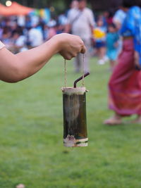 Close-up of hand holding drink in container over grass