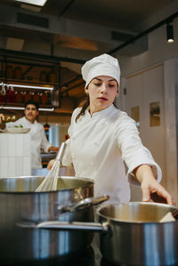 Young female chef working with colleagues in commercial kitchen