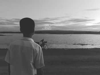 Rear view of man looking at sea against sky