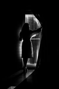 Rear view of silhouette woman standing at home
