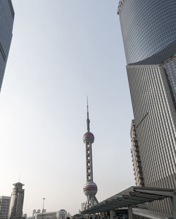 Low angle view of communications tower in city