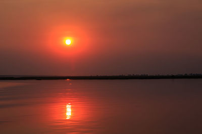 Scenic view of lake against orange sky during sunset