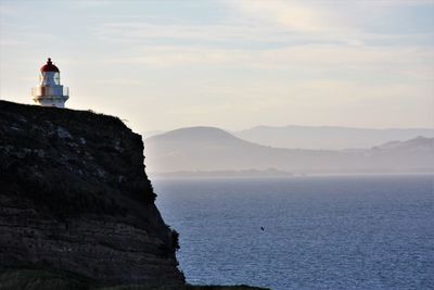 Lighthouse by sea against sky