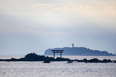 Lighthouse on beach by sea against sky