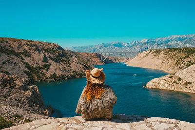 Rear view of woman looking at lake against mountain