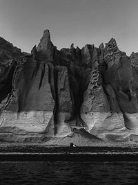 Rock formation in water against clear sky