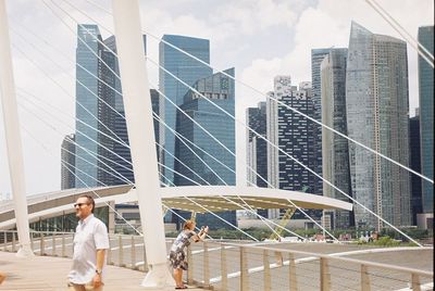 People on modern buildings in city against sky