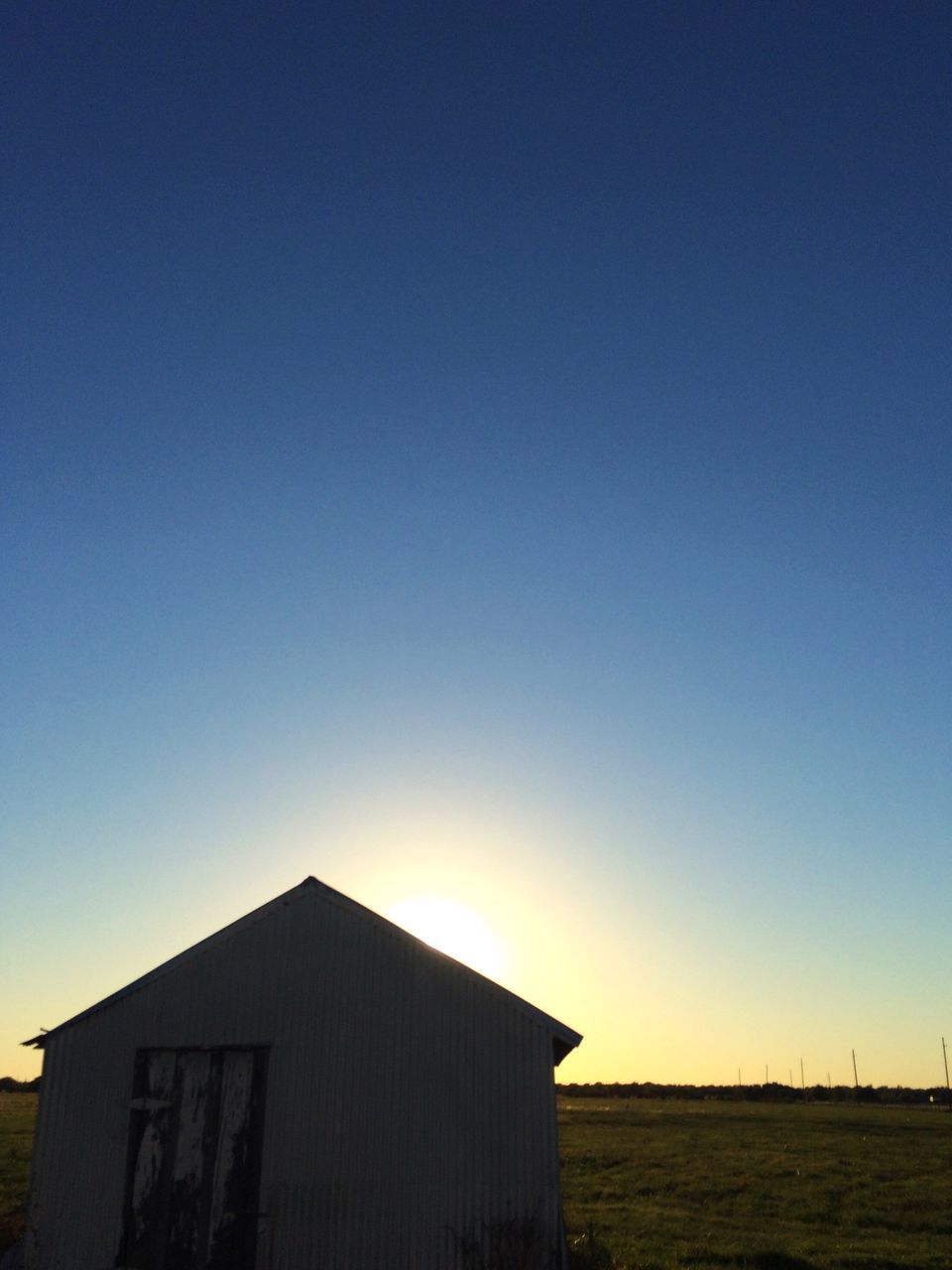 clear sky, copy space, blue, built structure, architecture, building exterior, sunset, sunlight, outdoors, tranquil scene, no people, scenics, tranquility, nature, beauty in nature, low angle view, house, day, idyllic, orange color