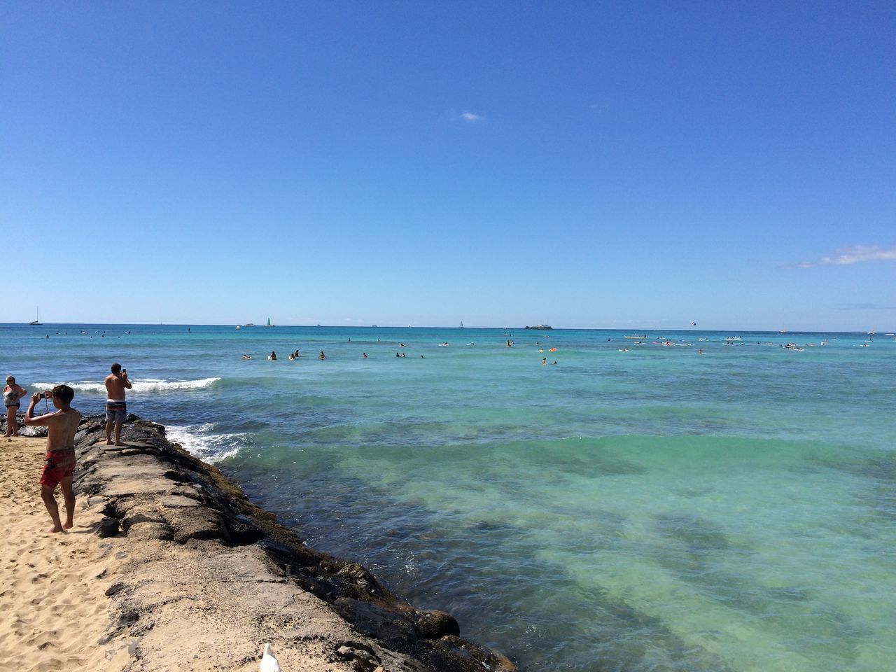 sea, water, beach, horizon over water, clear sky, copy space, blue, shore, large group of people, scenics, tranquil scene, tranquility, beauty in nature, nature, sand, vacations, incidental people, leisure activity, nautical vessel