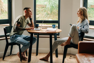 Young woman and man using electronic wireless devices for work and social media.