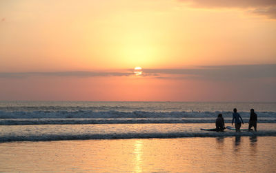 Silhouette people on beach against sky during sunset