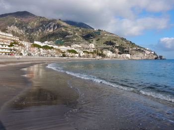 Scenic view of beach by city against sky