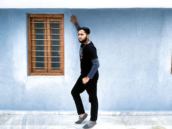 Full length of young man standing against building