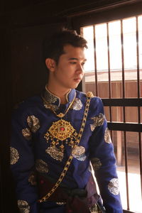 Close-up of young man standing against window