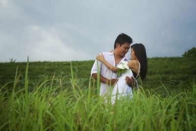 Couple kissing on field against sky