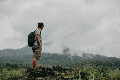 Side view of man looking at mountain range against sky