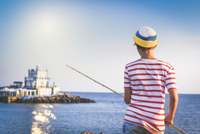 Rear view of boy fishing in sea