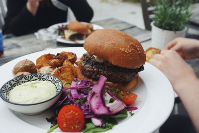 Close-up of burger with fried potato served in plate on table