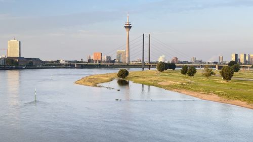 Bridge over river by buildings in city against sky