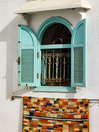 Handmade moroccan carpet hanging on the window of a carpet store in asilah