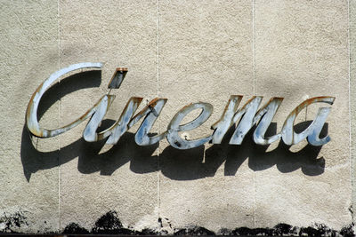 Damaged and rusty vintage cinema sign hanging on a wall