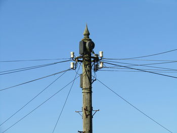 Power lines on pole against clear blue sky