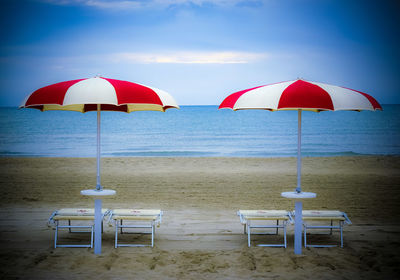 Parasols and empty seats at beach against sky