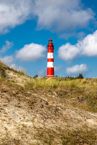 Lighthouse on field against sky