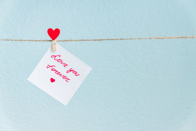 Close-up of heart shape text on paper against wall